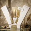 Een luxe productpresentatie van Risala For You Eau de Parfum, met de wit-gouden flacon van 100 ml met de kenmerkende vulpenpuntdop, gepresenteerd in de elegante geschenkverpakking met een verenveer en inktpot op een marmeren oppervlak.